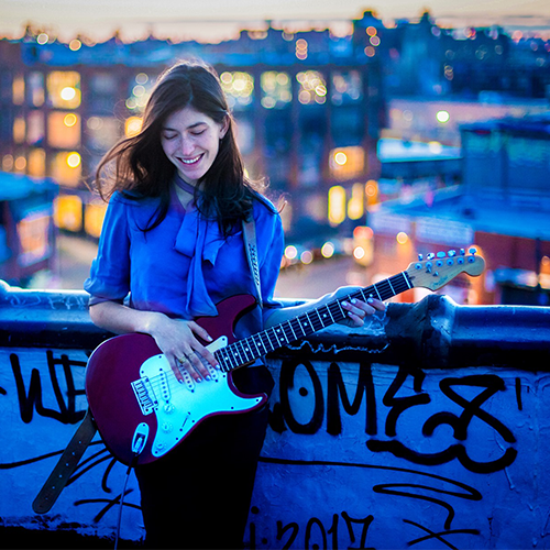 Juliet Garrett holding guitar on a bridge